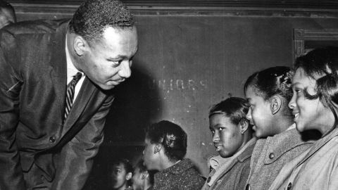 King Jr. bends to speak with a group of schoolgirls in a classroom in 1960.