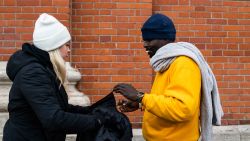 DETROIT, MICHIGAN - December 10, 2019: CEO of The Empowerment Plan Veronika Scott helps Gregory Benson,47, who is currently homeless, put on a new coat outside of the Pope Francis Center in downtown Detroit, Mich., on December 10, 2019. (Brittany Greeson for CNN)