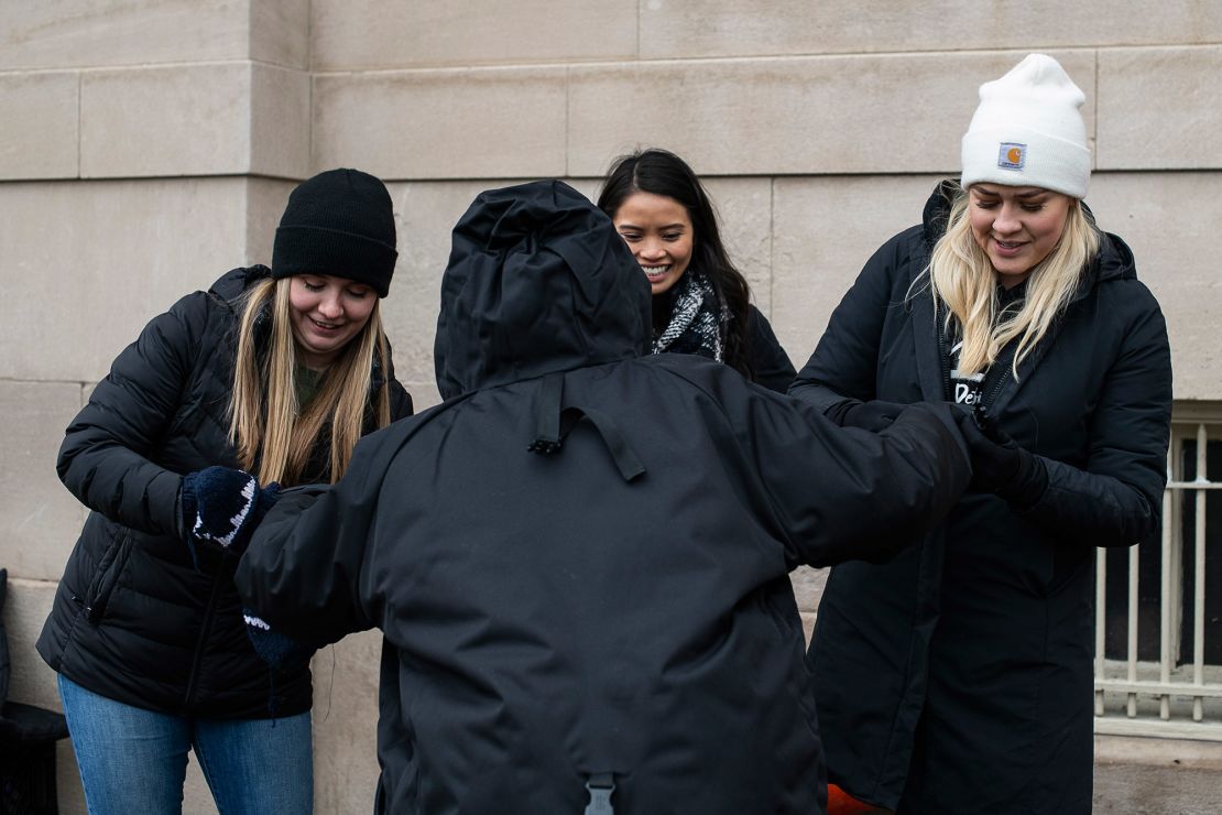 From left, Ellie Small and Mari Gener of MSU Detroit Street Care and Scott help a homeless woman with a new coat.