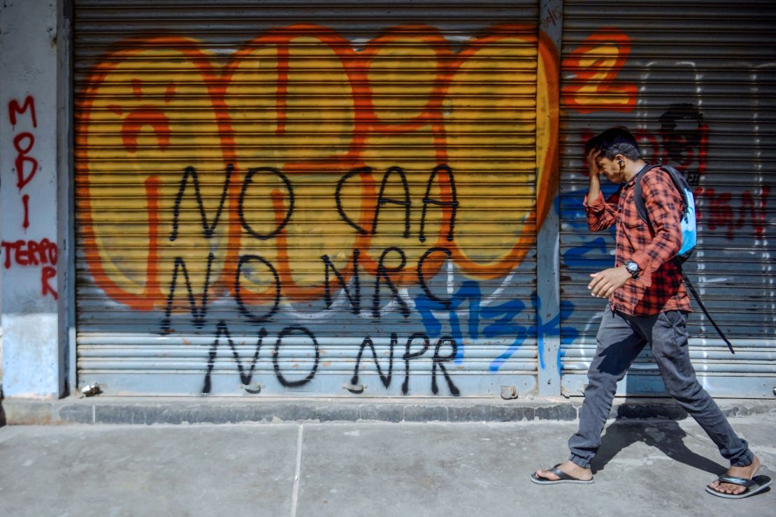 A pedestrian walks past graffiti condemning Indian Prime Minister Narendra Modi and India's new citizenship law, drawn by anonymous artists on the shutters and walls of Church Street, in Bangalore on January 14, 2020. 