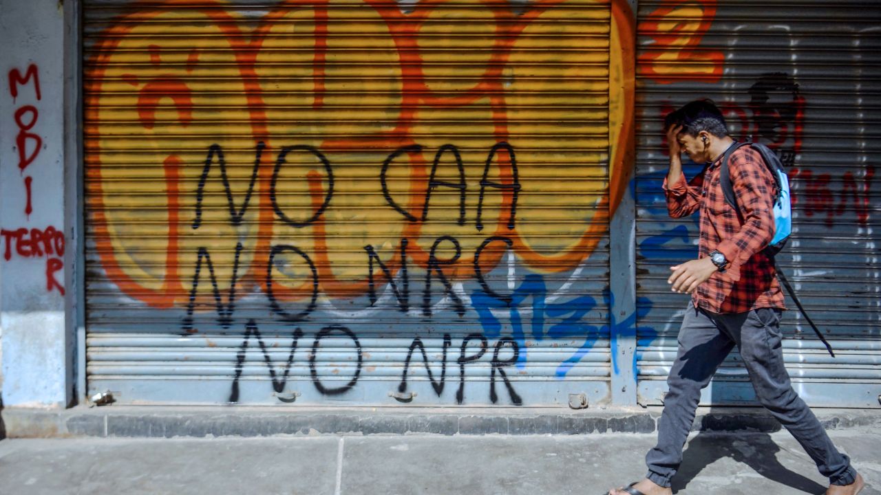 A pedestrian walks past graffiti condemning Indian Prime Minister Narendra Modi and India's new citizenship law, drawn by anonymous artists on the shutters and walls of Church Street, in Bangalore on January 14, 2020. 
