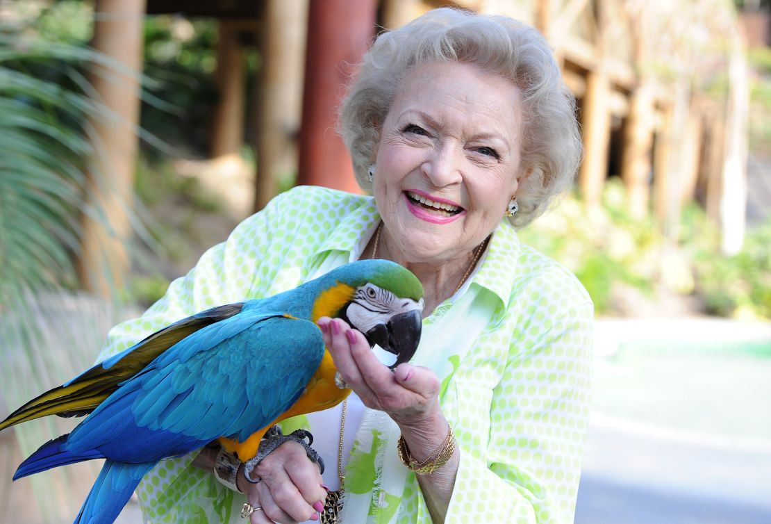 Betty White poses with a parrot. 
