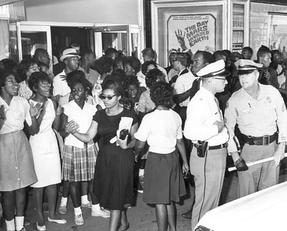 Picketing at the State Theater in Tallahassee in 1963; Patricia Stephens Due (in the black dress) and John Due (his head is visible behind the officer) are both pictured.