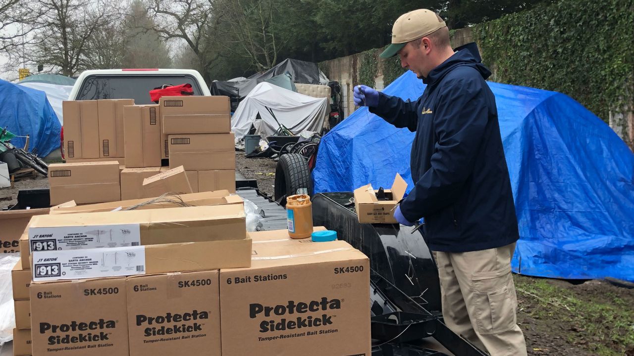 A pest control technician baits a trap with peanut butter.