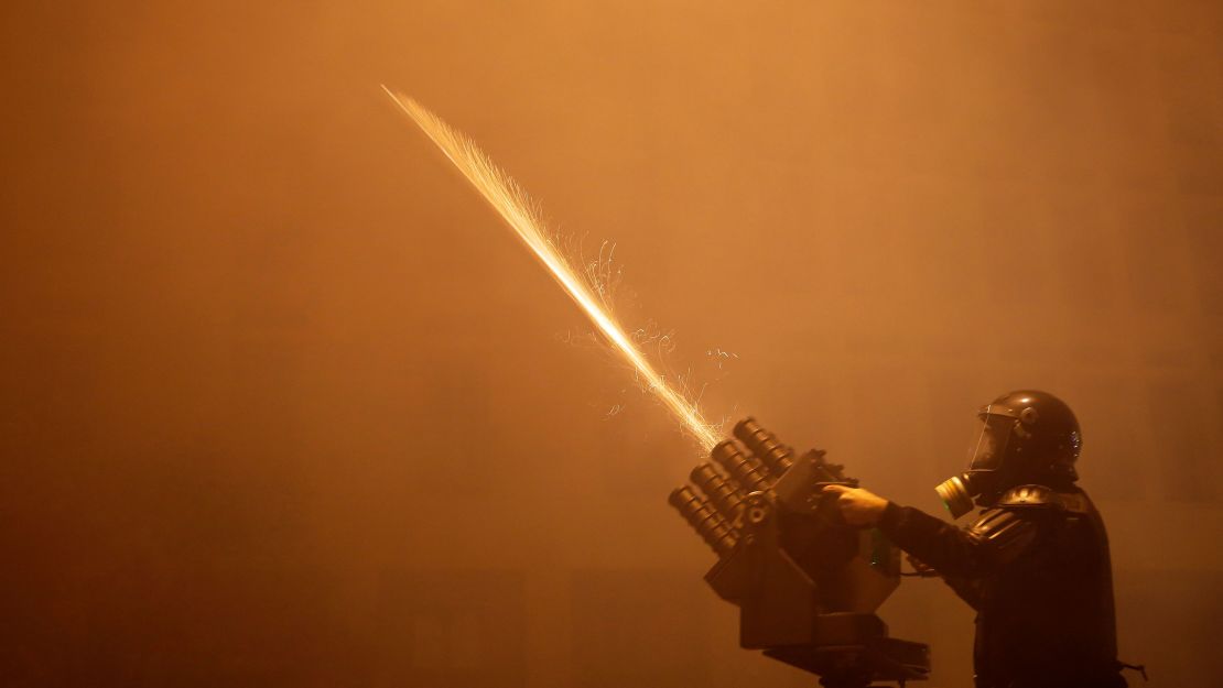 A riot police officer fires tear gas from a launcher against anti-government protesters trying to enter parliament square during a protest at a road leading to the parliament building in Beirut, Lebanon, Saturday, Jan. 18, 2020.