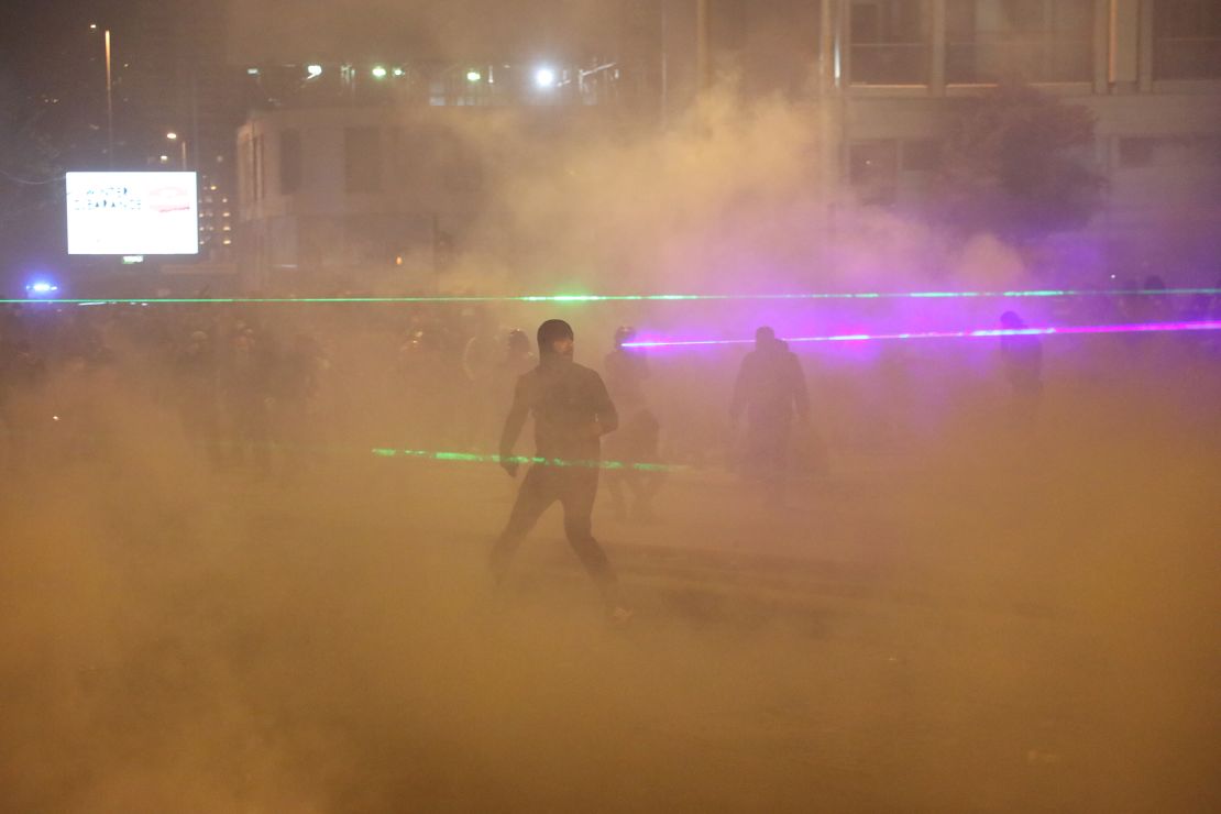 Laser beams scatter as they go through thick smoke and tear gas in central Beirut on Hamra street.