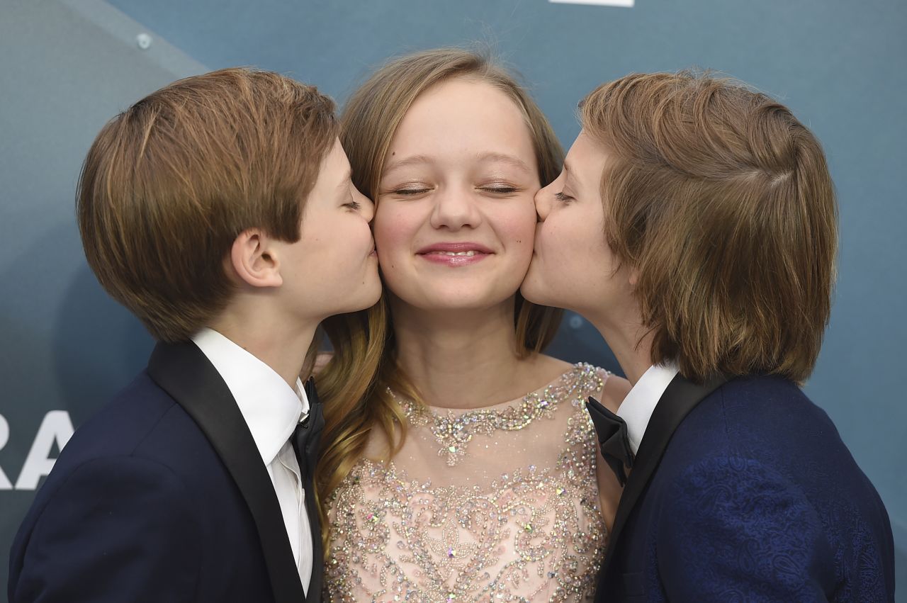 Cameron Crovetti, left, and Nicholas Crovetti kiss Ivy George.