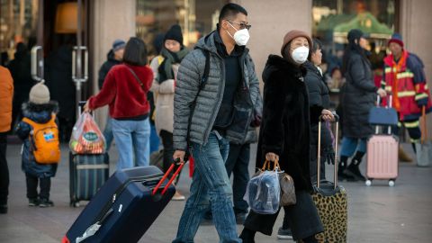 Travelers wear face masks as they walk outside of the Beijing Railway Station in Beijing, Monday, January 20, 2020.
