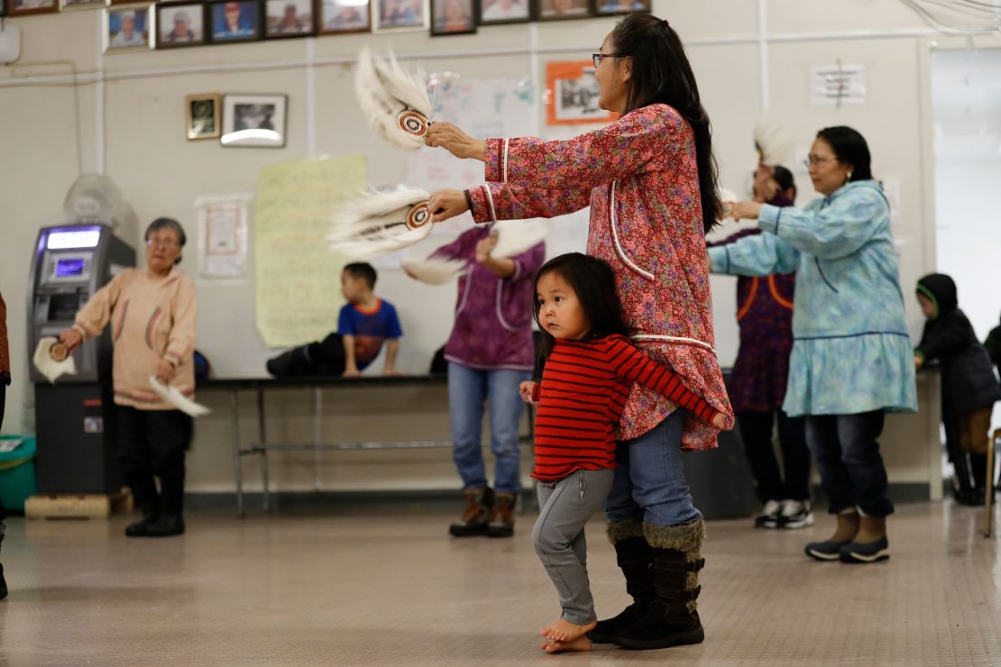 Liana Nicholai clings to her grandmother, Dora Nicholai, during an Alaska Native dance Monday in Toksook Bay.