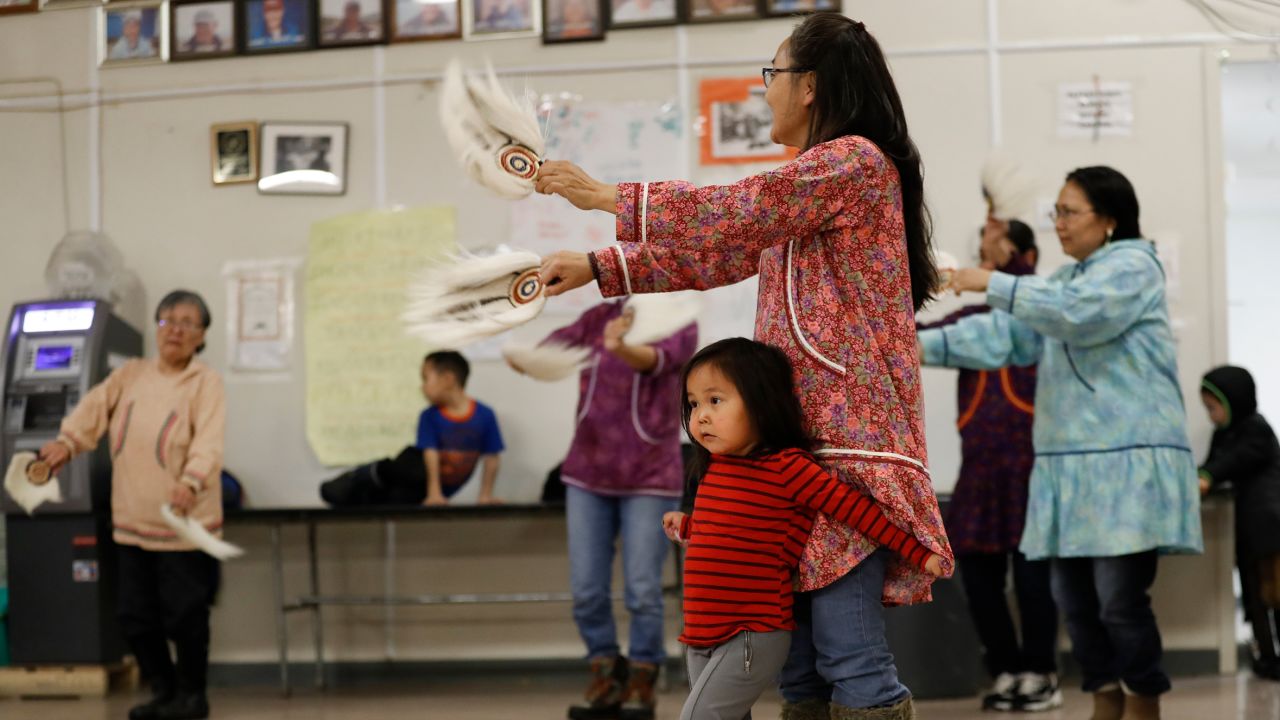 Liana Nicholai clings to her grandmother, Dora Nicholai, during an Alaska Native dance Monday in Toksook Bay.