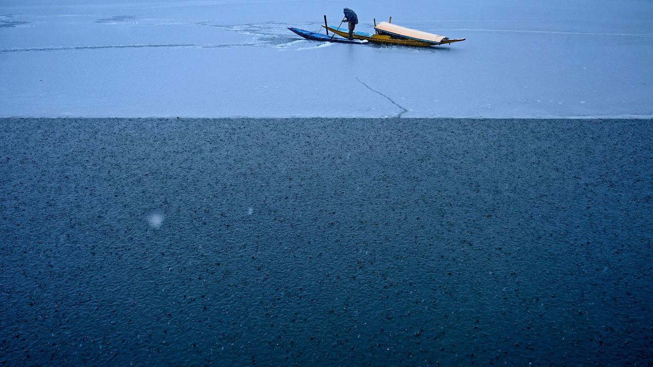 <strong>Srinagar, India:</strong> A man guides his boat along the water in Dal Lake, known as the "Lake of Flowers," as snow falls in the summer capital of Indian-controlled Kashmir.