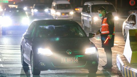 A staff member talks with a driver as he checks the body temperatures of passengers at an exit of a highway in Wuhan on Tuesday.