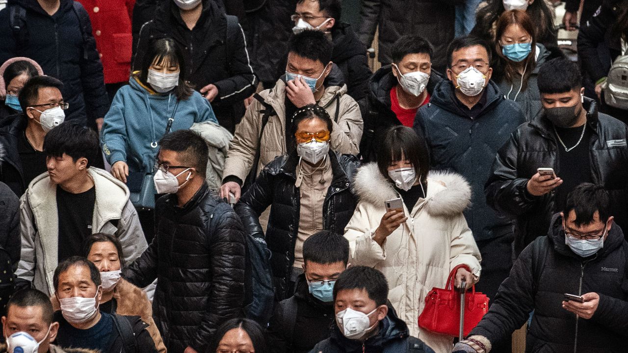 Chinese passengers, almost all wearing protective masks, arrive to board trains at a Beijing railway station on January 23, 2020.