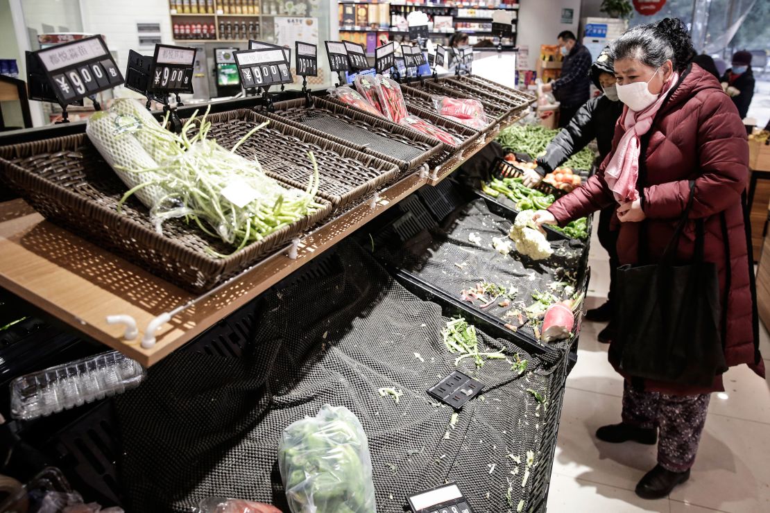 Residents wear masks to buy vegetables in a market in Wuhan.