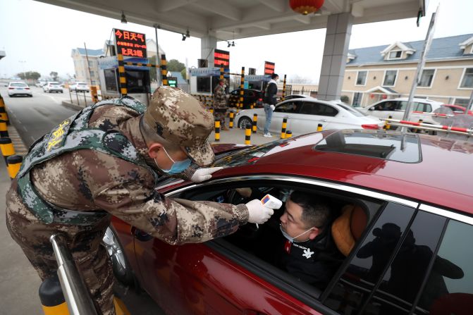 A militia member checks the body temperature of a driver in Wuhan on January 23, 2020.