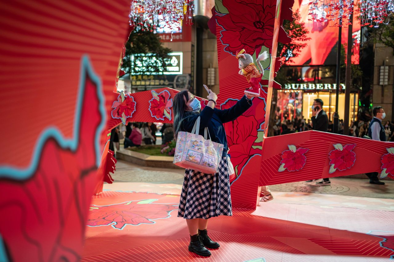 A pedestrian takes a photograph with her cellphone in front of a Lunar New Year decoration at a shopping mall in Hong Kong.