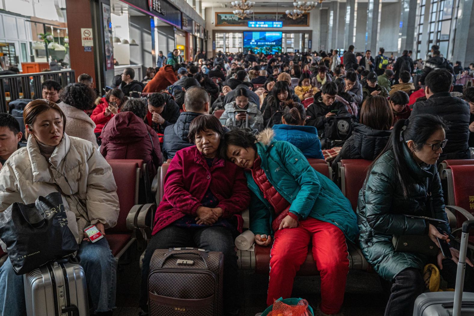 Chinese passengers wait with their luggage prior to boarding trains ahead of the Chinese Lunar New Year, or Spring Festival, at the Beijing Railway Station, on Friday, January 10.