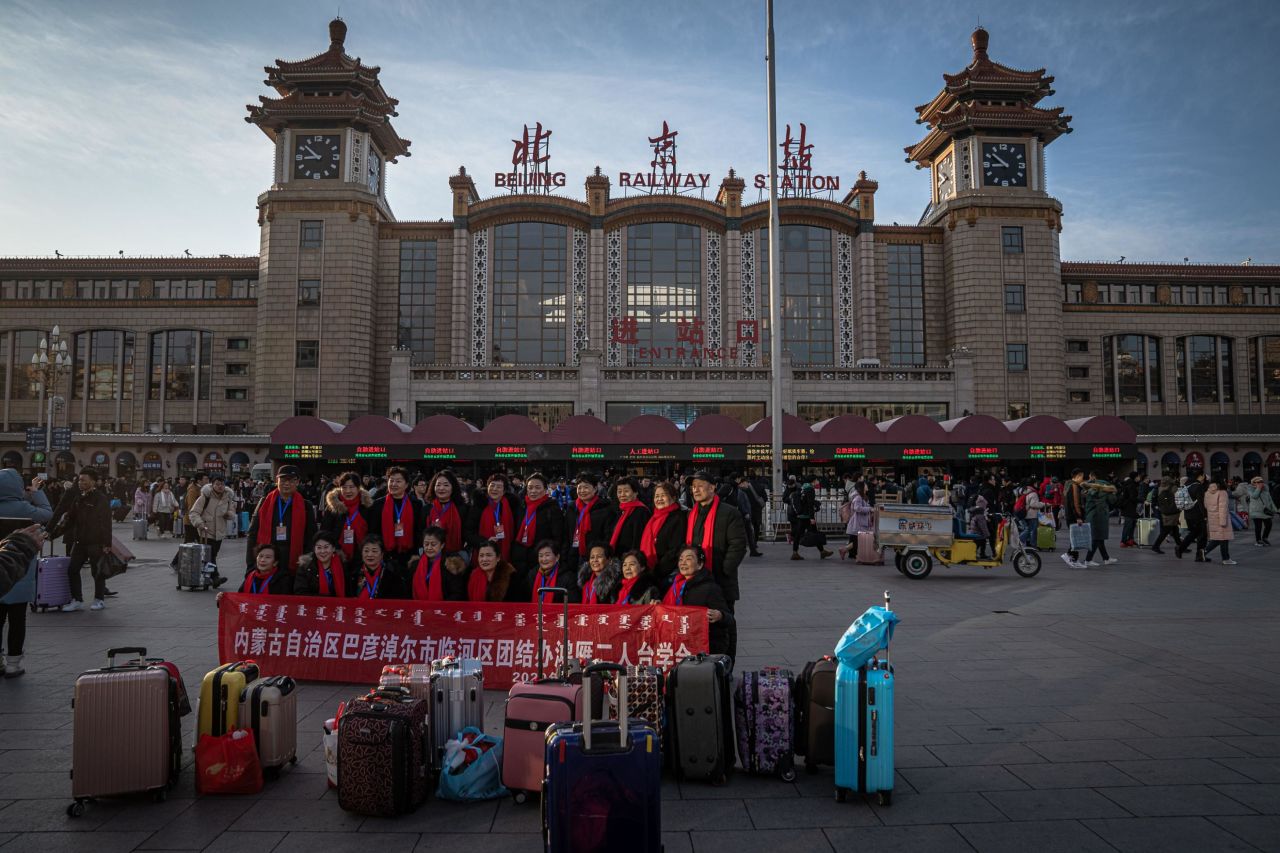 Chinese passengers hold a banner next to their luggage in front of the Beijing Railway Station on Friday, January 10.