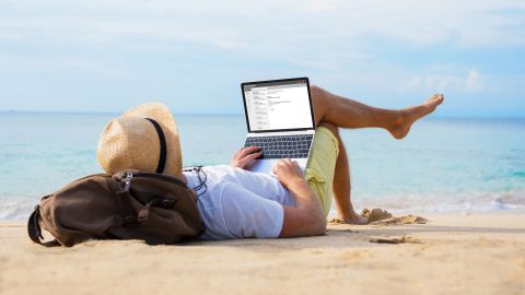 underscored man on laptop at beach