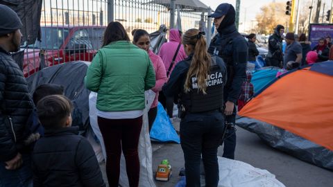 Juarez municipal police speak to asylum seekers camped out near Paso del Norte International Bridge, trying to convince them to go to shelters for migrants around the city on December 19, 2019 in Ciudad Juarez, Mexico. - In the mud and biting cold of a makeshift camp in the border city of Ciudad Juarez, more than 1,000 Mexican migrants had been waiting for weeks, some for months, for a chance to file for asylum in the United States. This week their numbers fell this week by half -- to around 700 -- as hundreds gave up hope of ever crossing the border. (Photo by Paul Ratje / AFP) (Photo by PAUL RATJE/AFP via Getty Images)