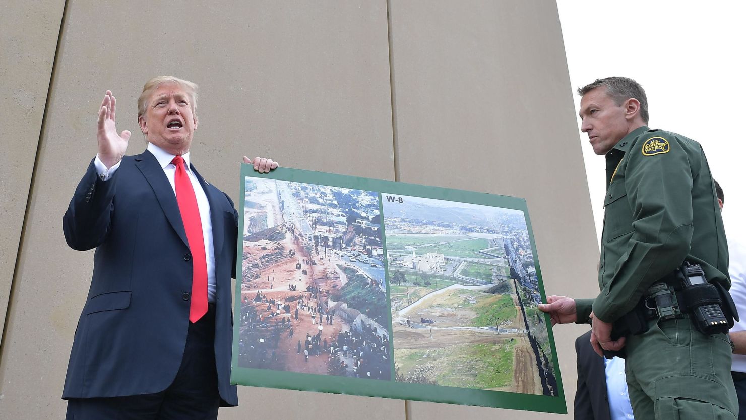 US President Donald Trump holds up a poster of before and after photos of a segment of the  border wall prototypes with Chief Patrol Agent Rodney S. Scott in San Diego, California on March 13, 2018. 
