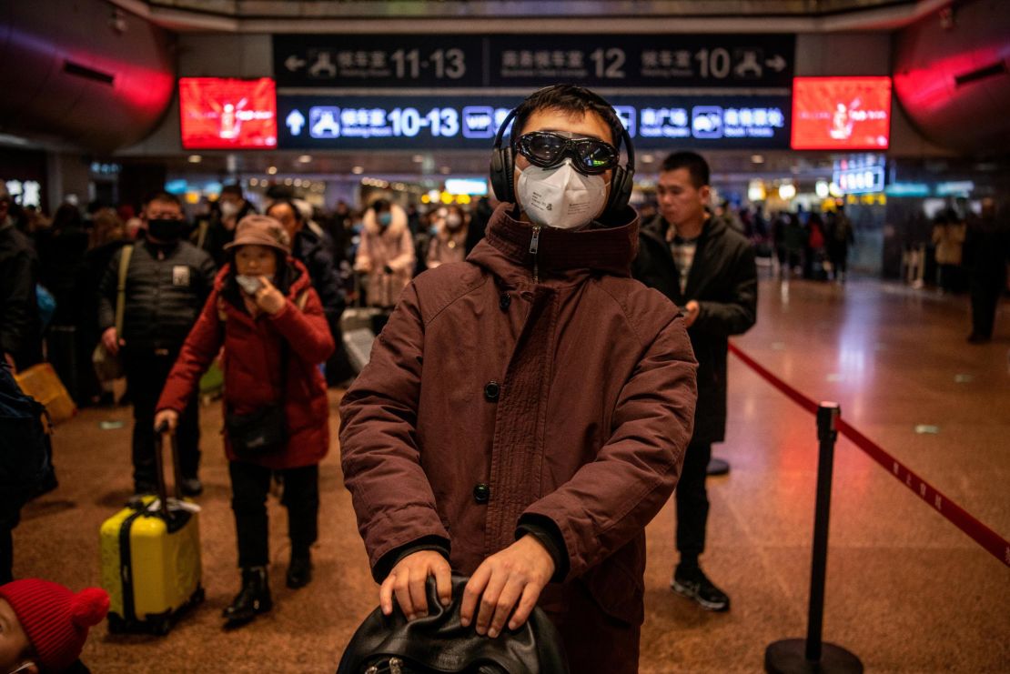 A Chinese man wears a protective mask and goggles before boarding a train at a Beijing railway station on January 23, 2020.