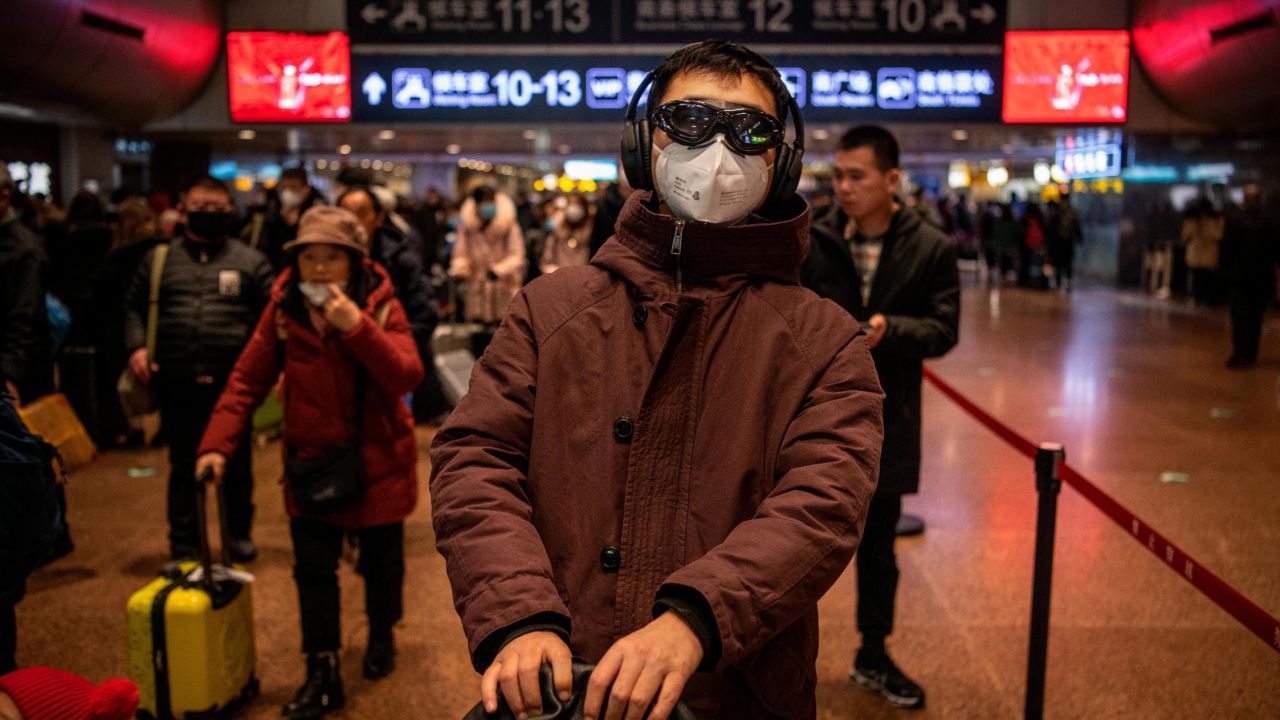 A Chinese man wears a protective mask and goggles before boarding a train at a Beijing railway station on January 23, 2020.