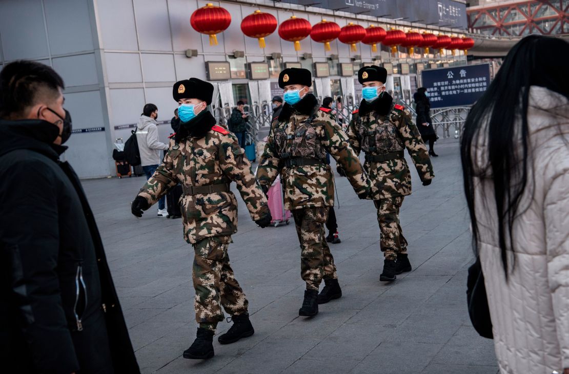 Chinese police officers wear protective masks as they patrol before the annual Spring Festival at a Beijing railway station on January 23, 2020.