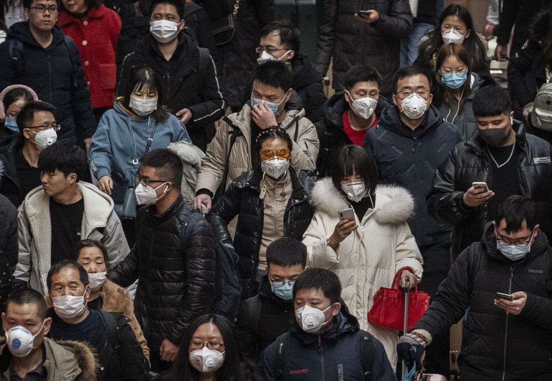 Chinese passengers, almost all wearing protective masks, arrive to board trains before the annual Spring Festival at a Beijing railway station on January 23, 2020.