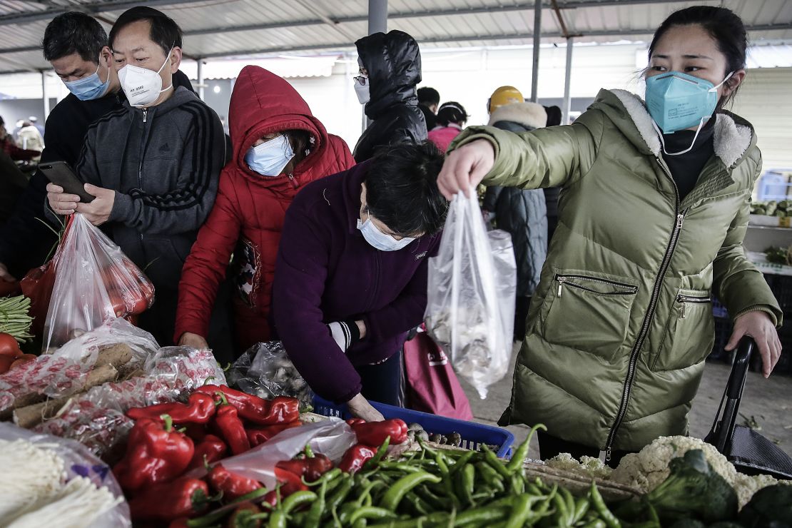 Residents wear masks to buy vegetables at a market in Wuhan on January 23, 2020.