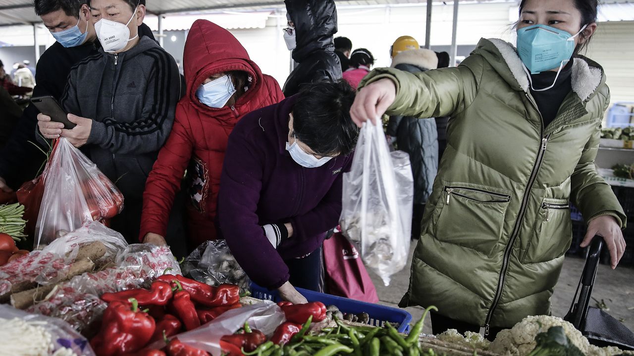 Residents wear masks to buy vegetables at a market in Wuhan on January 23, 2020.