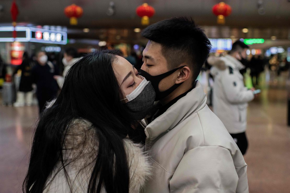 A couple, wearing protective masks, kisses goodbye as they travel for the Lunar New Year holidays at a railway station in Beijing.