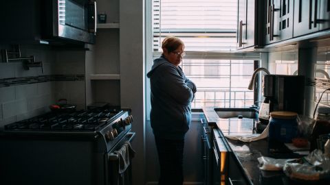 Mirta Santiago Cortés, 67, waits for a pot of coffee to brew in the Manhattan apartment she shares with more than a dozen family members from Puerto Rico.