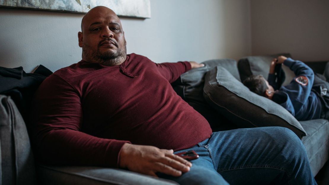 Alejandro Quiles, 40, a retired police officer from the town of Guánica, sits in the living room of the New York apartment he shares with 16 family members from Puerto Rico.