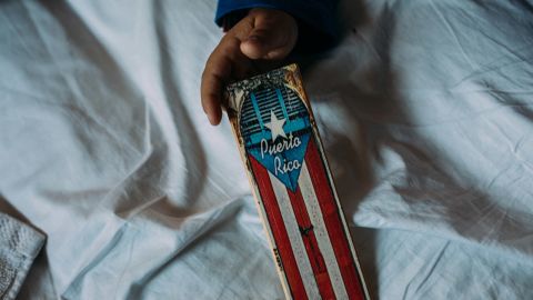 Alexander Quiles, 7, holds the cover of a dominoes box on an air mattress in the living room of his aunt Jodie Roure's apartment in Manhattan.