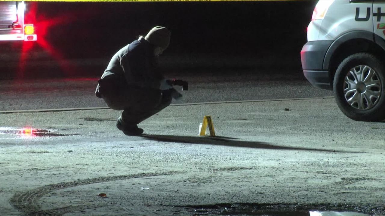 Authorities investigate the scene of the shooting where two young men were killed.