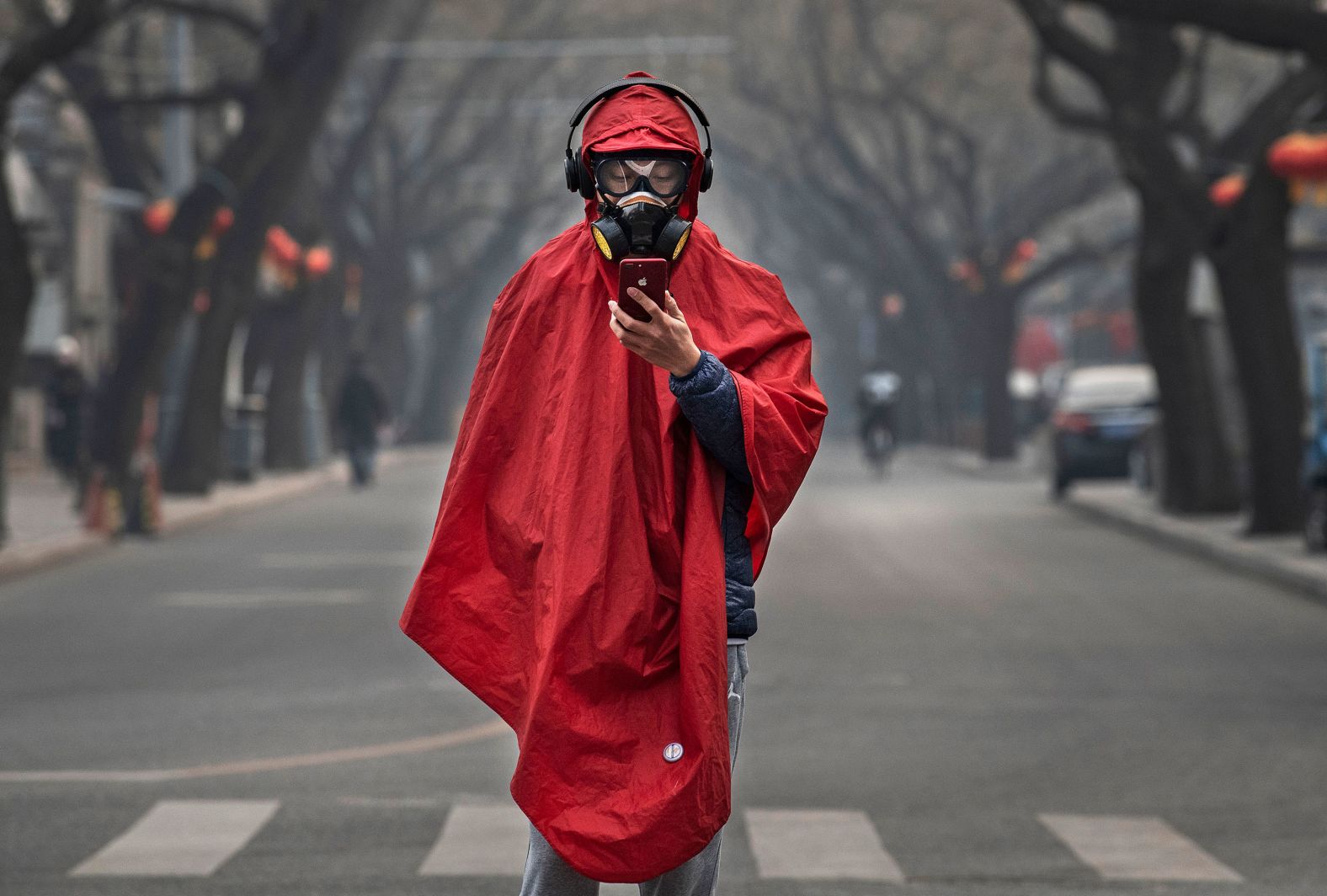 A person wears a protective mask, goggles and coat as he stands in a nearly empty street in Beijing on January 26, 2020.