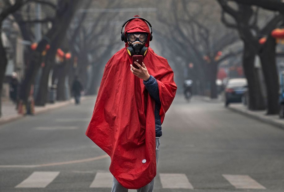 A person wears a protective mask, goggles and coat as he stands in a nearly empty street in Beijing on January 26.