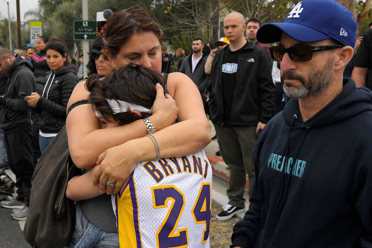 Elana Hirschman hugs her 11-year-old son Bryan as her husband Craig stands by Sunday near the scene of the deadly helicopter crash in Calabasas, California.