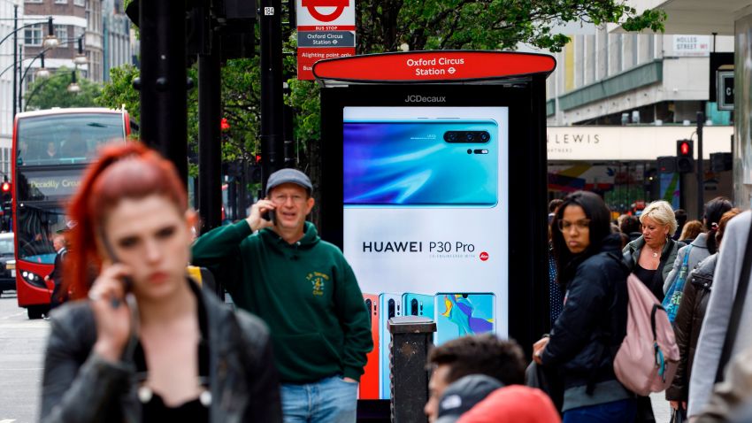 Pedestrians use their mobile phones near a Huawei advert at a bus stop in central London on April 29, 2019. - British Foreign Secretary Jeremy Hunt has urged caution over the role of China's Huawei in the UK, saying the government should think carefully before opening its doors to the technology giant to develop next-generation 5G mobile networks. His comments come after Prime Minister Theresa May conditionally allowed China's Huawei to build the UK 5G network, information that was leaked to a newspaper from top secret discussions between senior ministers and security officials, a leak that has caused a scandal that has rocked Britain's splintered government. (Photo by Tolga Akmen/AFP/Getty Images)