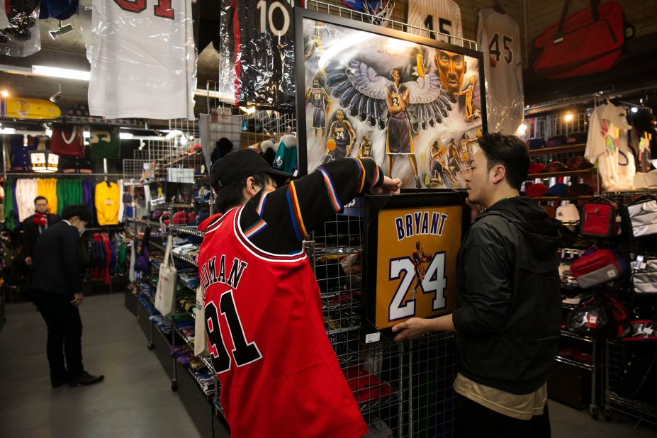 Store manager Satoshi Kanazawa, right, and Kazuhiro Taguchi hang a poster showing an image of former NBA basketball player Kobe Bryant at Selection in Tokyo on Monday, January 27.