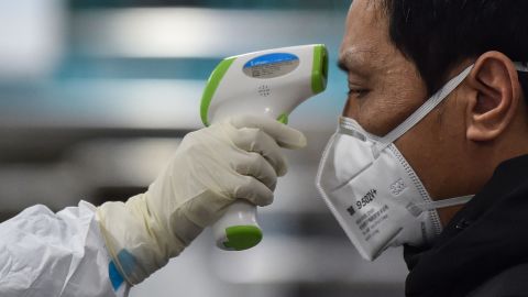 A medical staff member takes the temperature of a man at the Wuhan Red Cross Hospital in Wuhan on January 25, 2020.