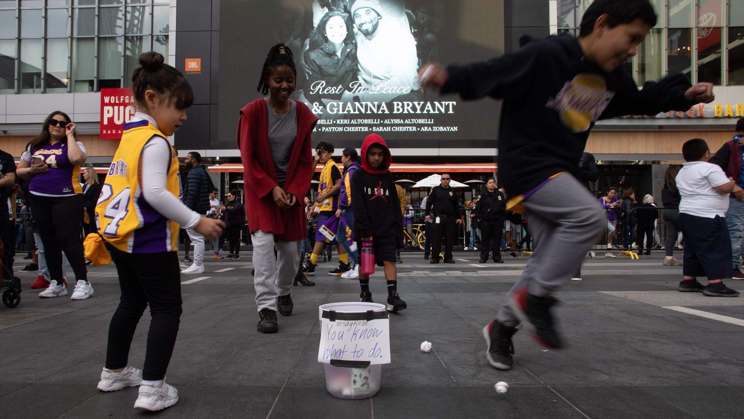 Children plays basket with paper balls in a trash can in front of a makeshit memorial for former NBA and Los Angeles Lakers player Kobe Bryant and his daughter Gianna Bryant, at LA Live plaza in front of Staples Center in Los Angeles on January 27, 2020. 