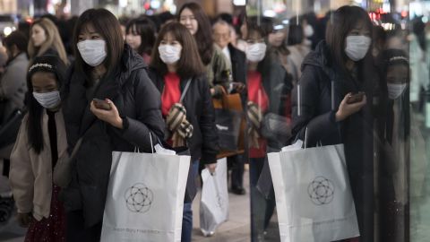 People wearing masks walk through the Ginza shopping district in Tokyo. 