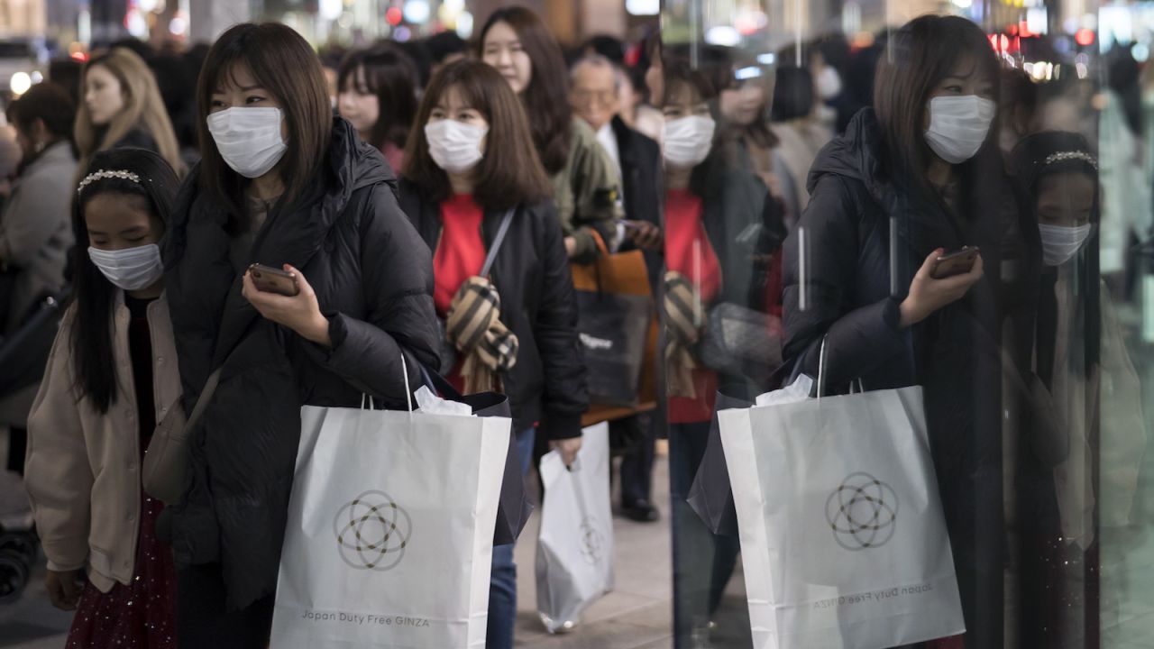 People wearing masks walk through the Ginza shopping district on January 24 in Tokyo. The city is a popular destination for Chinese tourists during the Lunar New Year holiday.