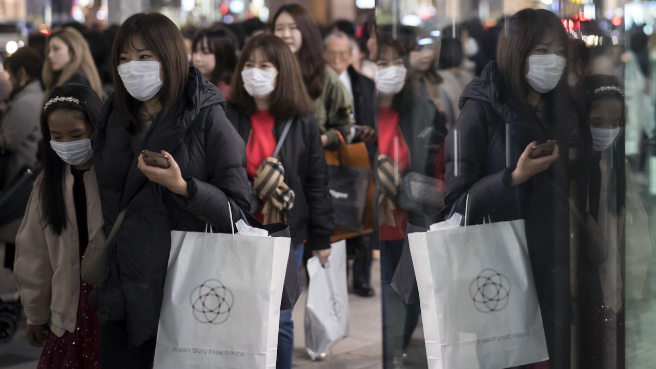 People wearing masks walk through the Ginza shopping district in Tokyo.
