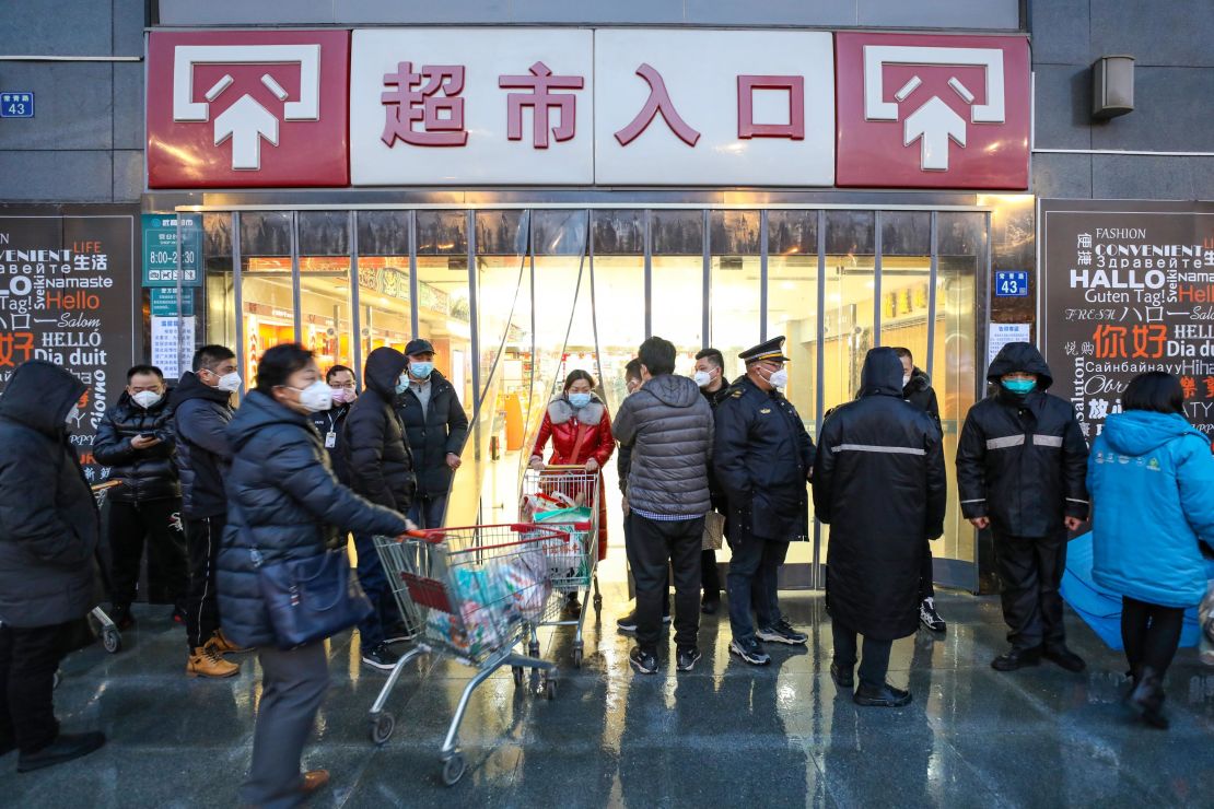 Masked shoppers stop by the entrance to a supermarket in Wuhan.