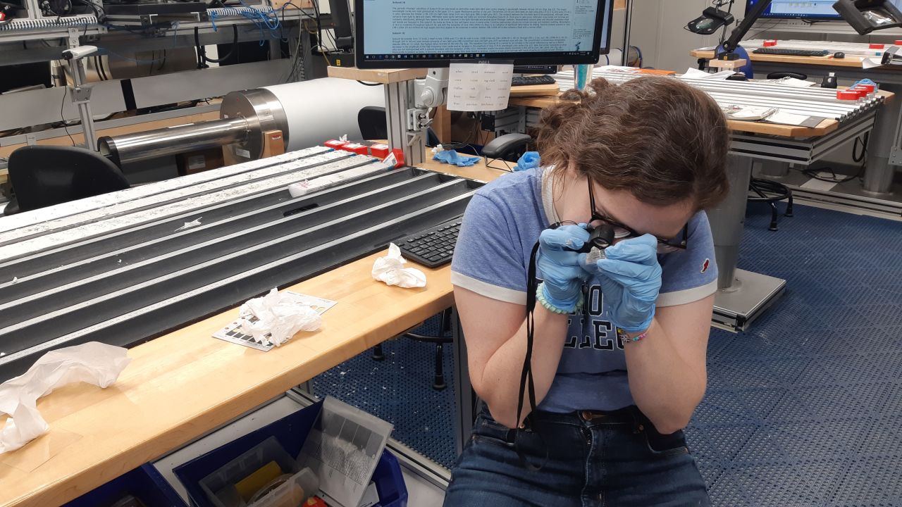 Sedimentologist Laura Haynes inspects a sample on Expedition 378. Haynes specializes in taking the chemistry of fossil shells and using it to reconstruct seawater acidity at previous stages of history.