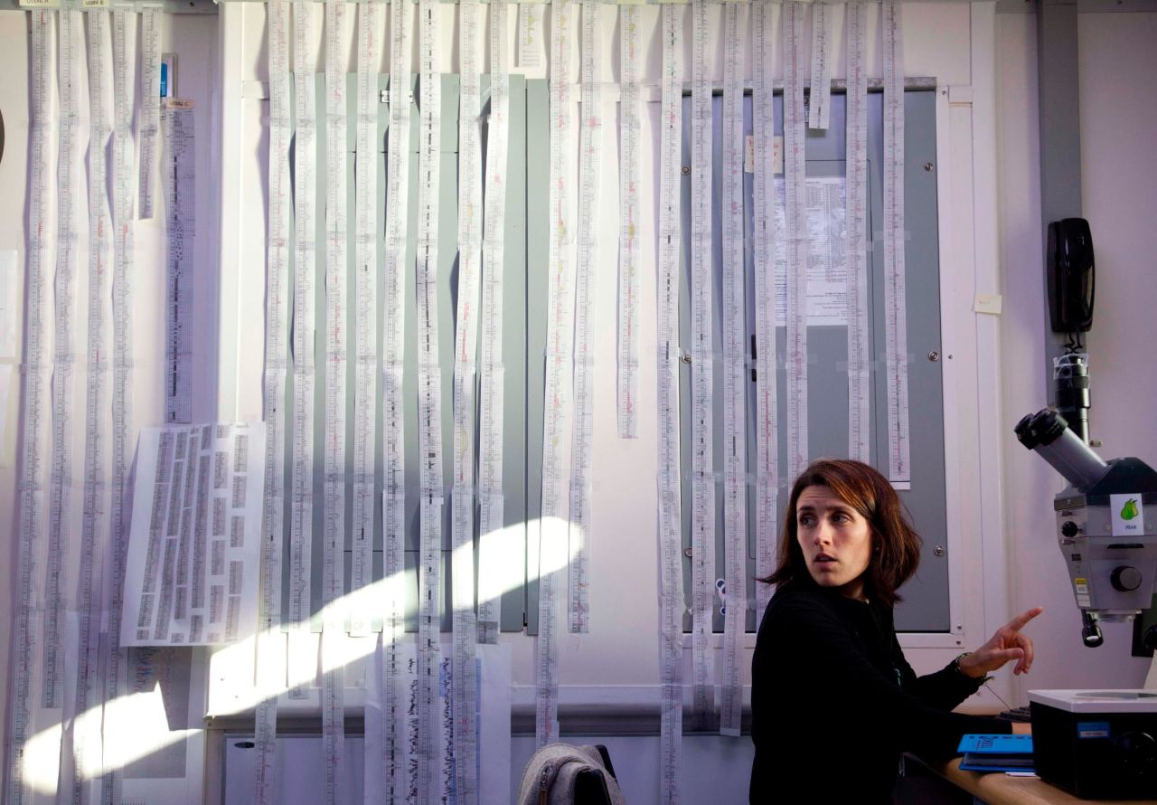 Sedimentologist Emmanuelle Duscassou in 2012 with columns of hand-drawn core logs on display behind her. Part of the appeal for scientists on board is that their work has immediate value, said Clement.