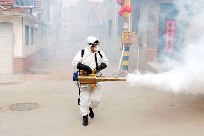 A volunteer wearing protective clothing disinfects a street in Qingdao, China, on January 29, 2020.